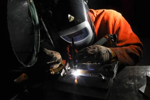 Certified MIG welder fabricating structural steel frame in SGI welding section