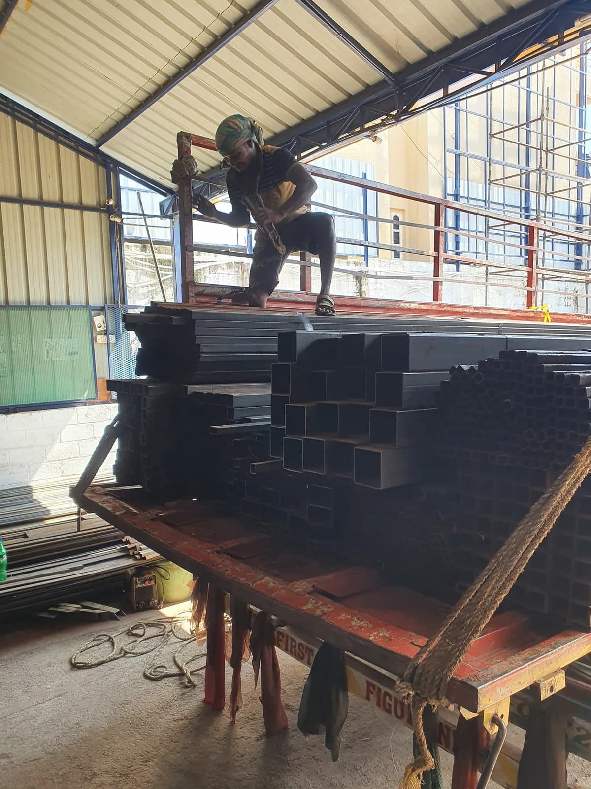 Operator handling square hollow sections during material preparation